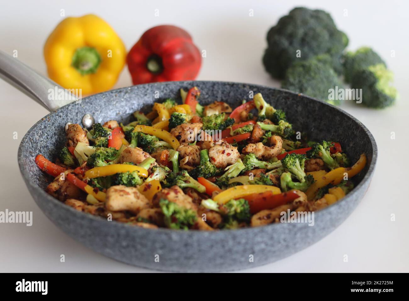 Dans une poêle, ajouter les légumes frits avec le poulet. Cubes de poulet frits à l'air avec poivrons et brocoli sautés. Pris avec le brocoli de petits pains Banque D'Images