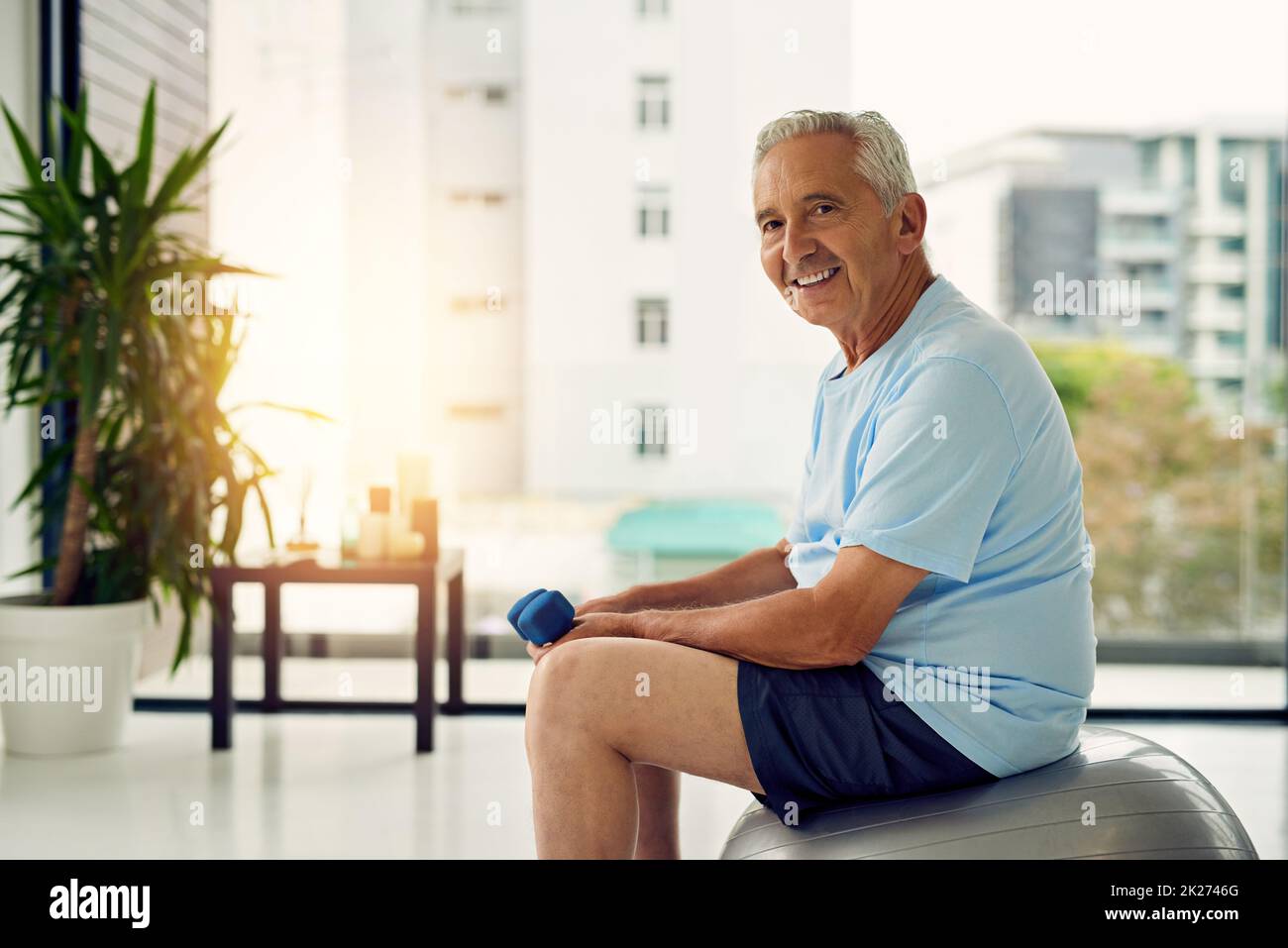 Mon corps, mon investissement.Portrait d'un homme en forme souriant tout en soulevant des poids au centre de fitness. Banque D'Images