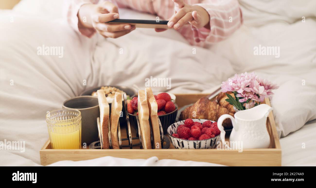 Pour tous les amateurs de cuisine.Photo courte d'une femme prenant une photo de son petit déjeuner au lit à la maison. Banque D'Images