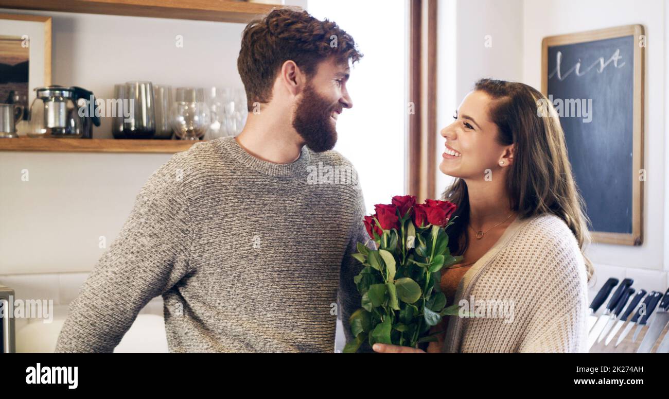 Belles roses pour ma belle femme.Un jeune homme surprend sa femme avec un bouquet de roses à la maison. Banque D'Images