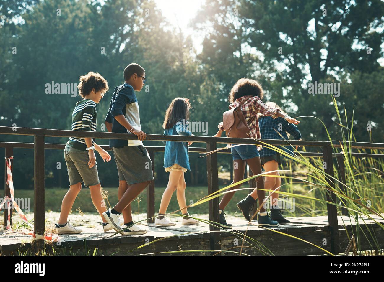 L'aventure, ici, nous venons.Photo d'un groupe d'adolescents marchant sur un pont dans la nature au camp d'été. Banque D'Images