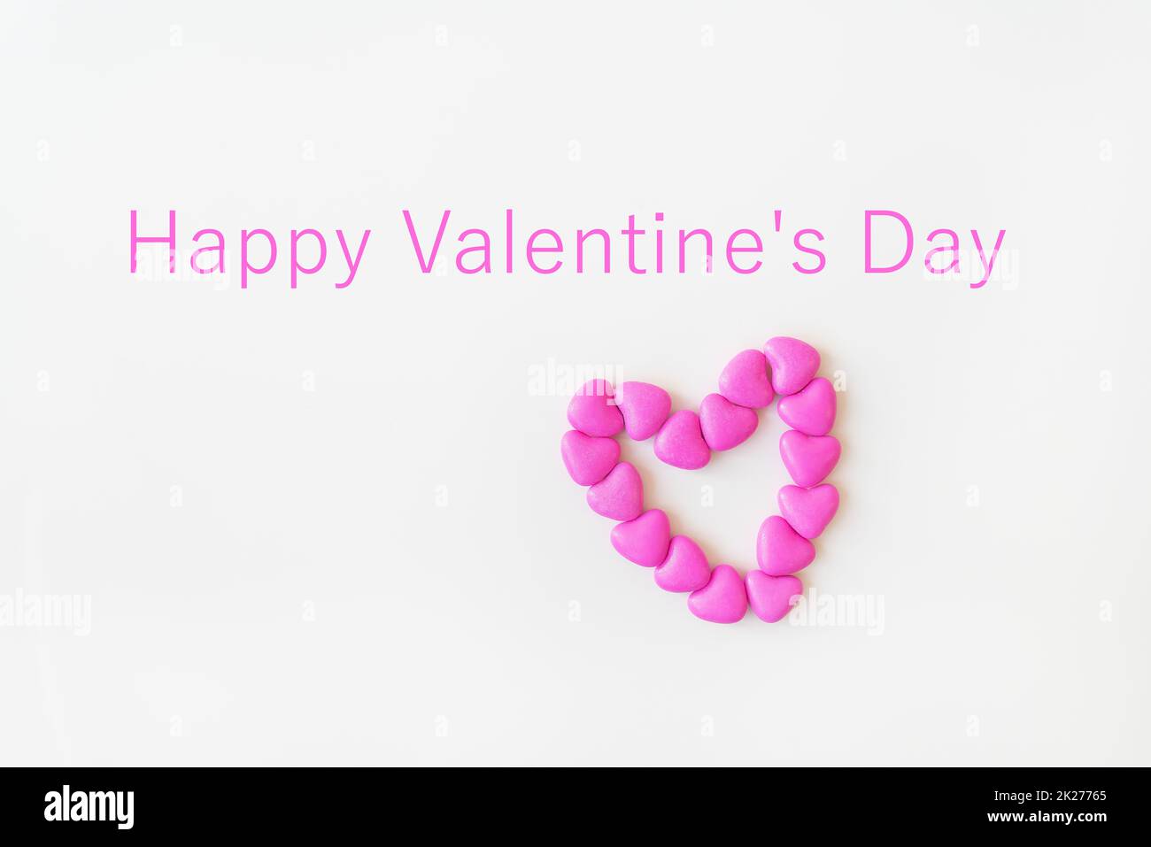 Saint-Valentin motif de jour fond plat couché dessus vue de coeur en forme de bonbons roses éparpillés sur fond blanc. Inscription Bonne Saint Valentin. Banque D'Images