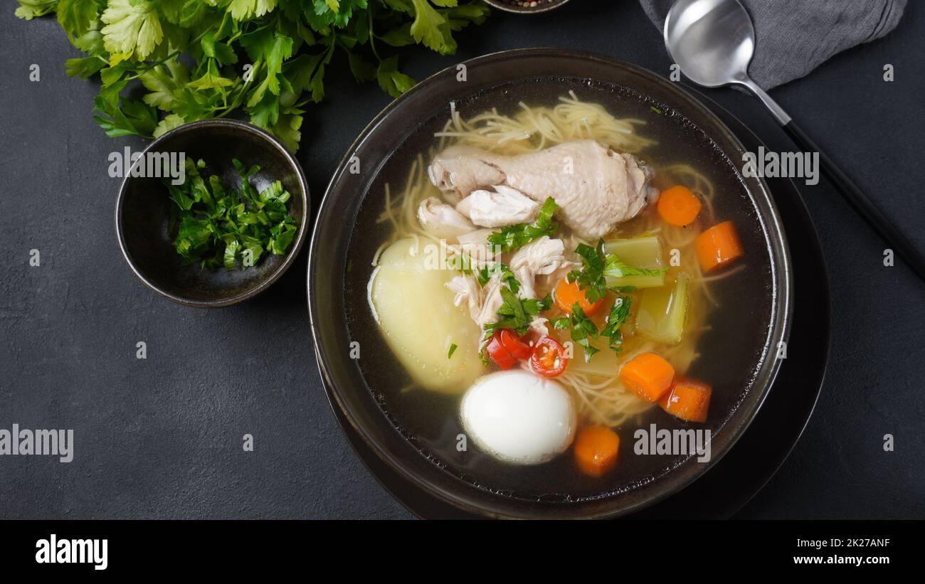 Soupe de nouilles de poulet au Caldo de Gallina avec œufs durs et herbes.La soupe péruvienne classique de nouilles de poulet. Banque D'Images