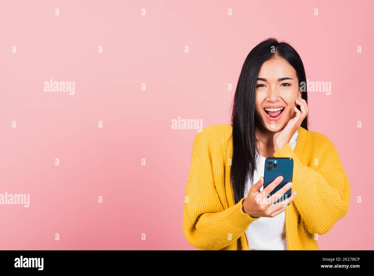 Joyeux portrait asiatique beau mignon jeune femme adolescent souriant excité en utilisant le studio de téléphone mobile intelligent tourné isolé sur fond rose, la femme thaïlandaise surprise de faire le geste gagnant sur le smartphone Banque D'Images