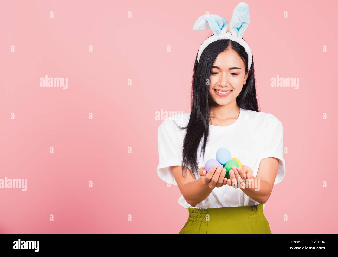 Femme souriante portant des oreilles de lapin tenant des œufs de Pâques colorés cadeau sur les mains Banque D'Images
