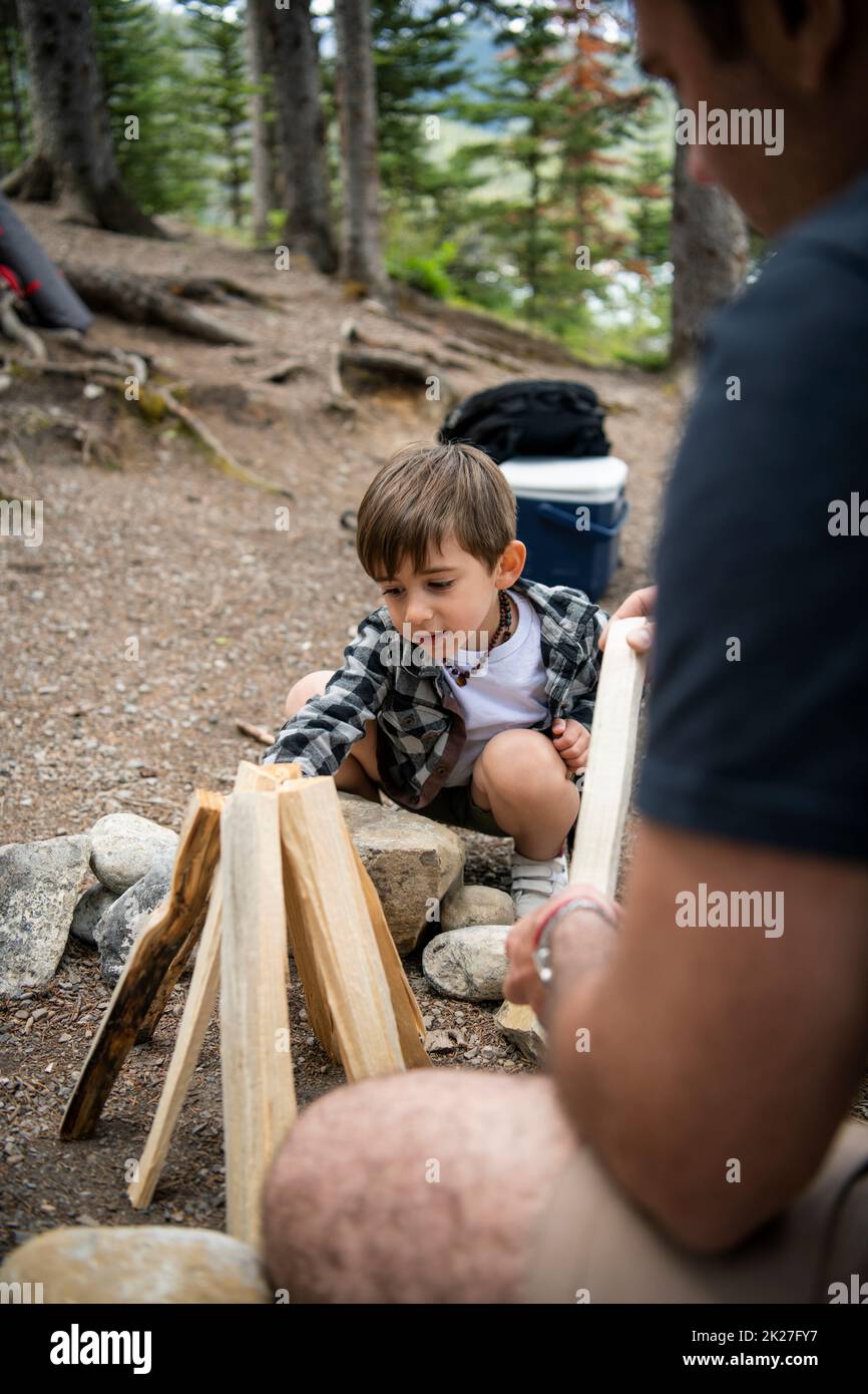Le père qui regarde le fils organise du bois de chauffage pour le feu de camp au camping Banque D'Images