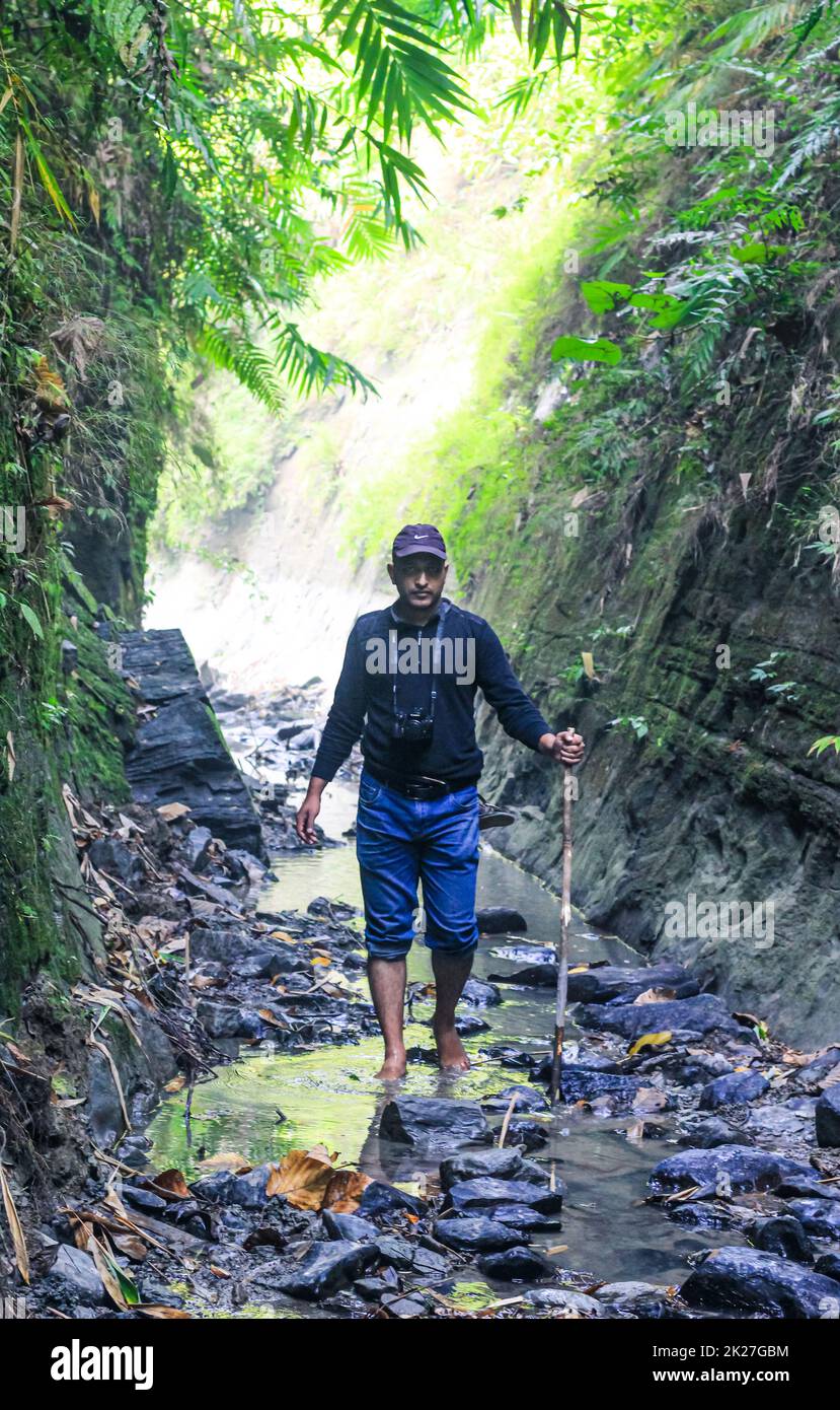 Homme marchant au niveau de la crique dans la forêt avec leurs chaussures à la main. Randonneurs randonnée dans la forêt. Randonneurs marchant dans la forêt à côté de la rivière de montagne. Banque D'Images