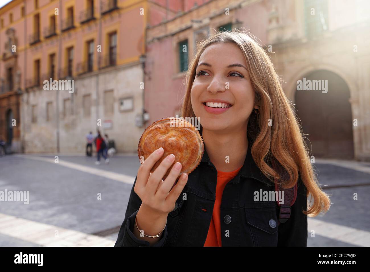 Cuisine de rue à Murcia, Espagne.Belle fille touristique tenant le pastel de carne murciano (Meurcian meatloaf) dans la rue Murcia, Espagne. Banque D'Images