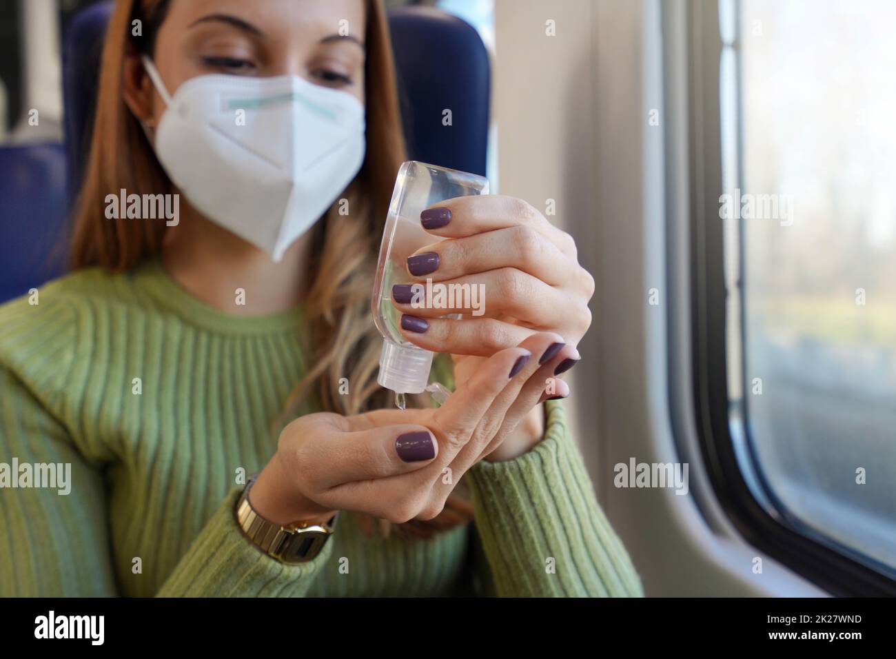 Femme d'affaires avec masque médical utilisant l'alcool gel assainisseur mains dans les transports publics. Concept antiseptique, hygiène et soins de santé. Concentrez-vous sur la main avec un flacon de gel d'alcool. Banque D'Images