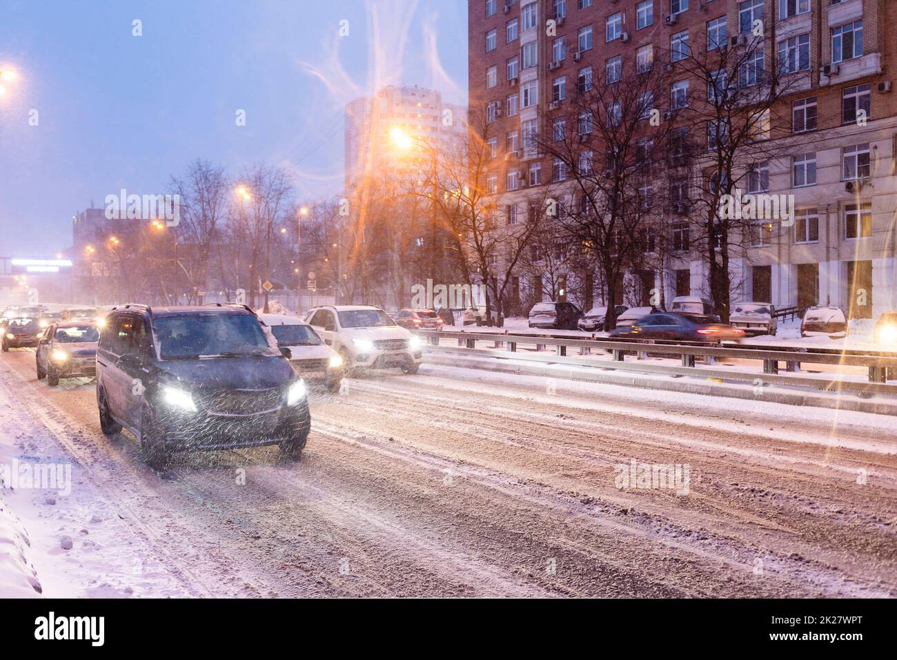 les voitures circulent sur une route enneigée glissante en chute de neige Banque D'Images