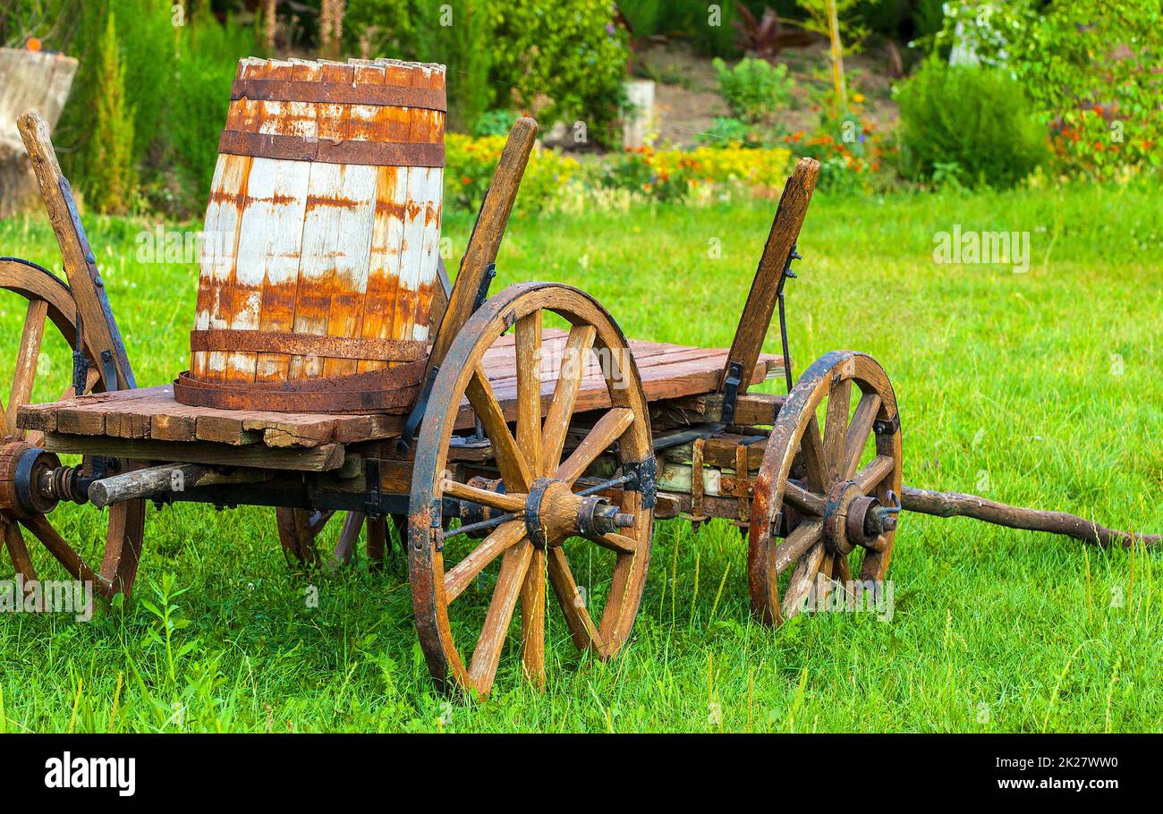 Ancien chariot en bois avec un fût sur l'herbe verte. Mise au point sélective Banque D'Images