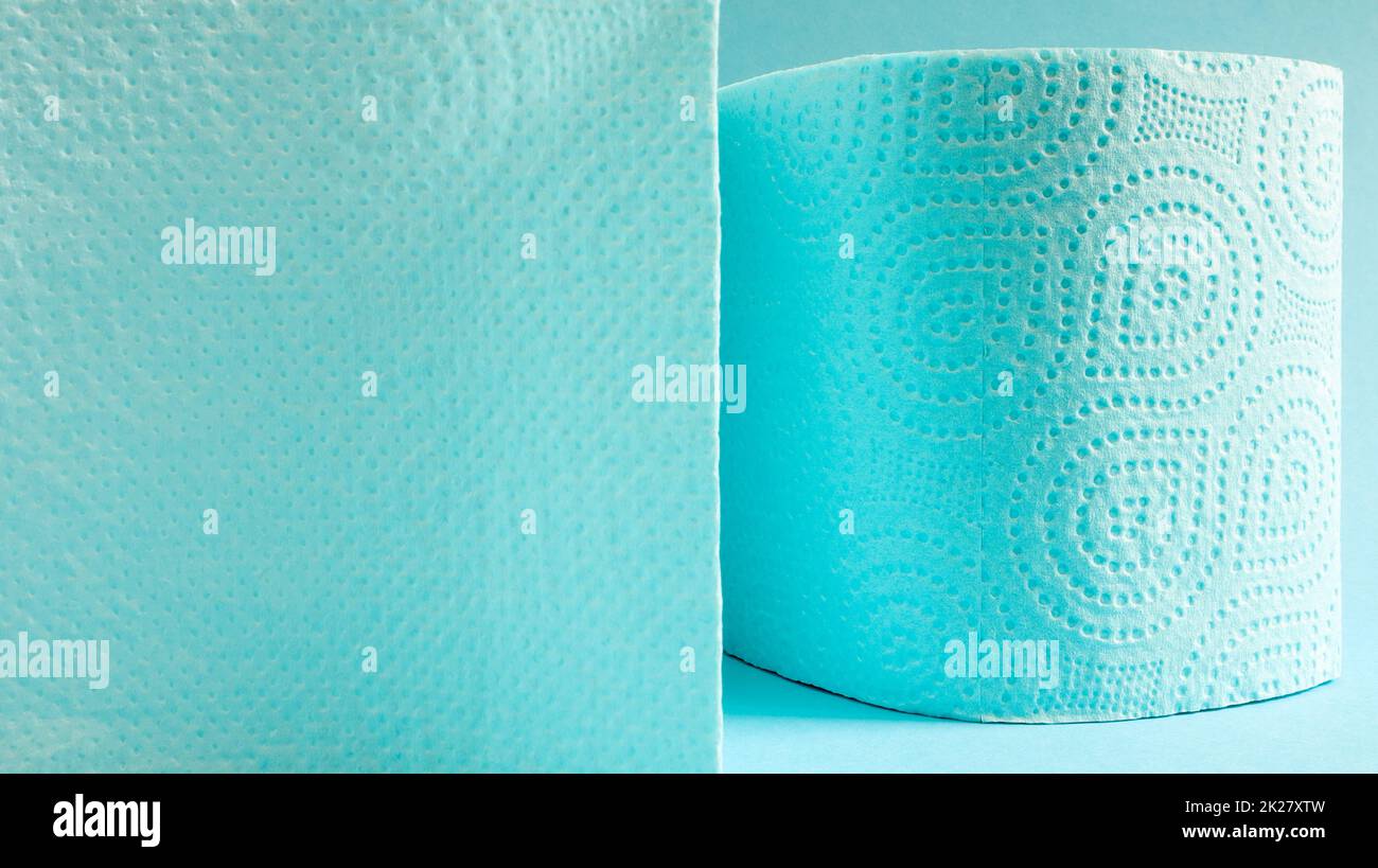 Rouleau bleu de papier toilette moderne sur fond bleu. Un produit en papier sur un manchon en carton, utilisé à des fins sanitaires à partir de cellulose avec des découpes pour faciliter le déchirement. Dessin en relief. copier l'espace. Banque D'Images