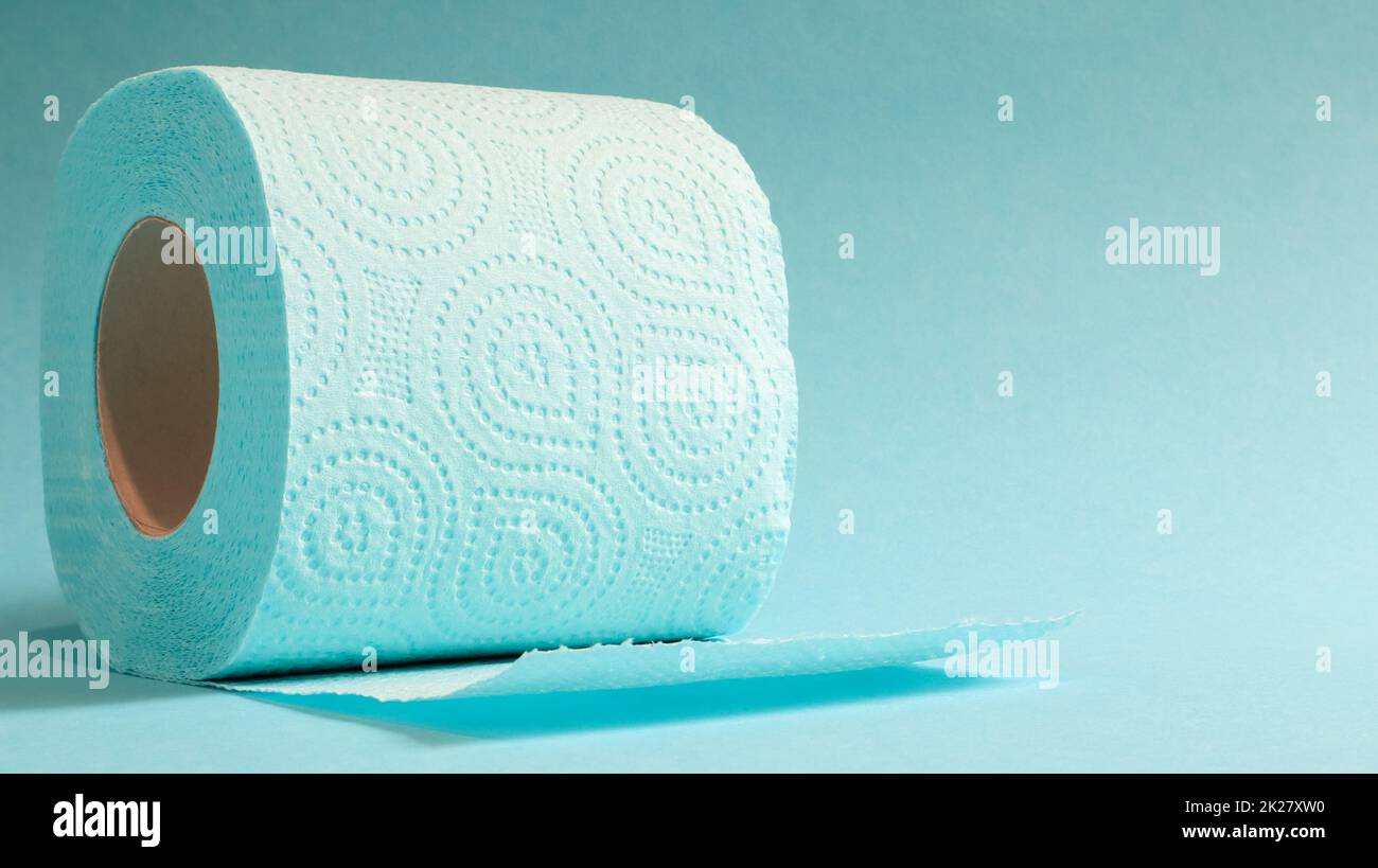 Rouleau bleu de papier toilette moderne sur fond bleu. Un produit en papier sur un manchon en carton, utilisé à des fins sanitaires à partir de cellulose avec des découpes pour faciliter le déchirement. Dessin en relief. copier l'espace. Banque D'Images