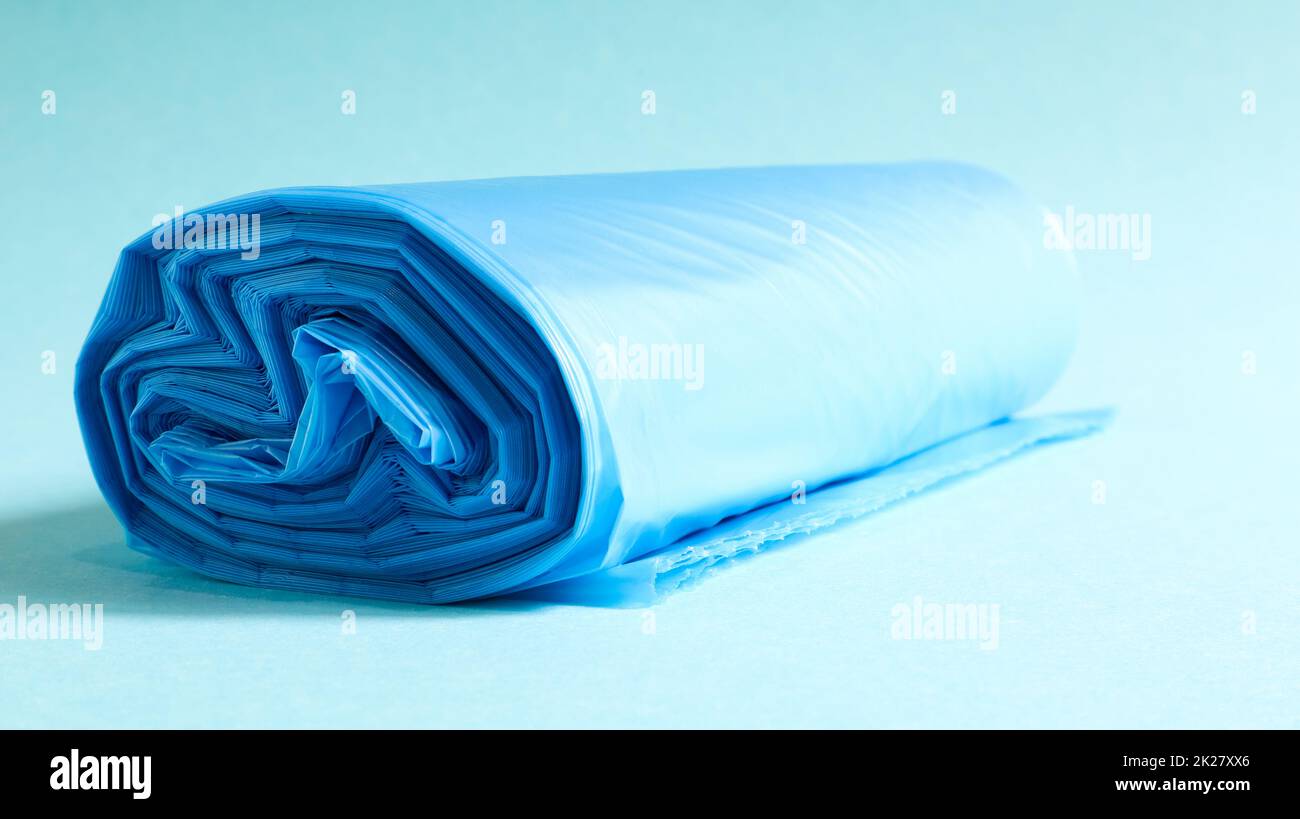 Un rouleau de sacs à ordures en plastique bleu sur fond bleu. Sacs qui sont conçus pour accueillir les ordures dans eux et utilisés à la maison et placés dans divers conteneurs à ordures. Banque D'Images