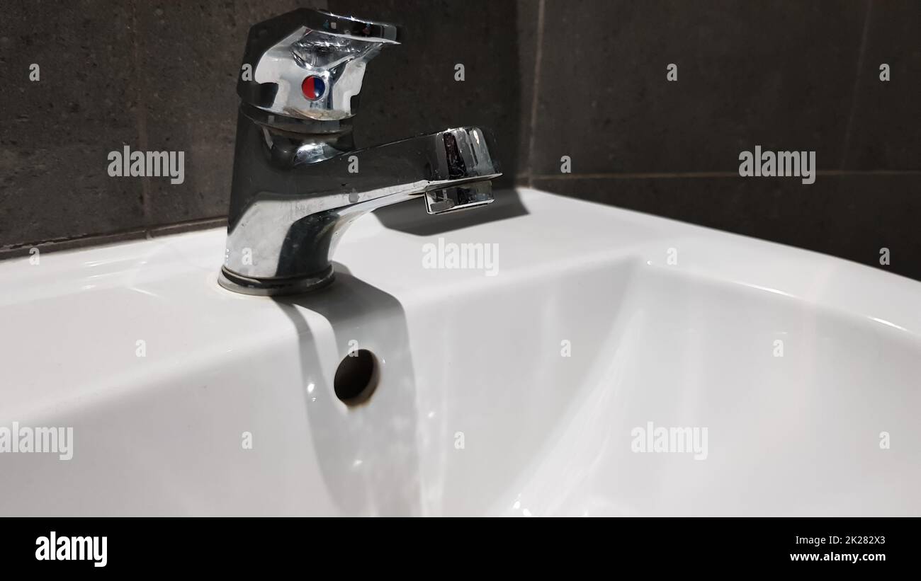 lavabo en céramique blanche avec robinet en chrome dans les toilettes avec carreaux gris Banque D'Images