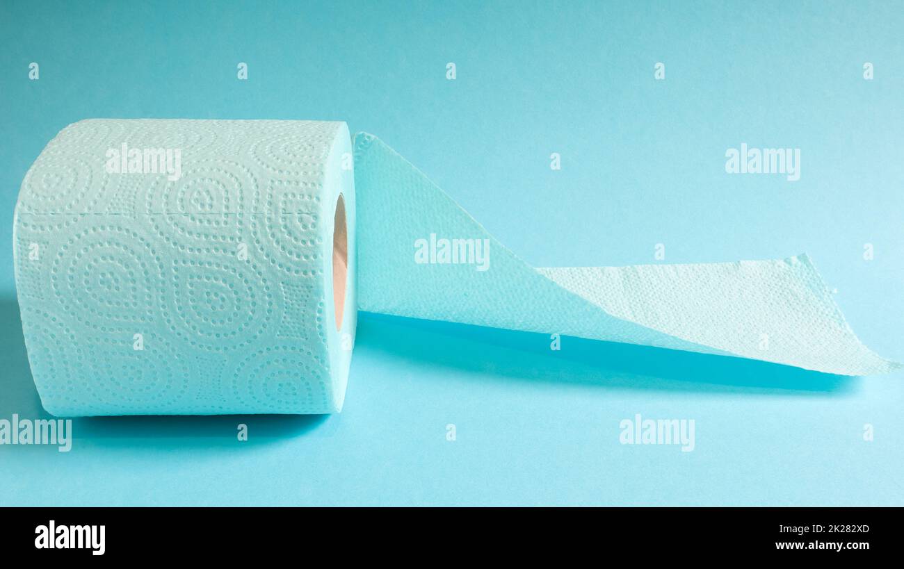 Rouleau bleu de papier toilette moderne sur fond bleu. Un produit en papier sur un manchon en carton, utilisé à des fins sanitaires à partir de cellulose avec des découpes pour faciliter le déchirement. Dessin en relief Banque D'Images