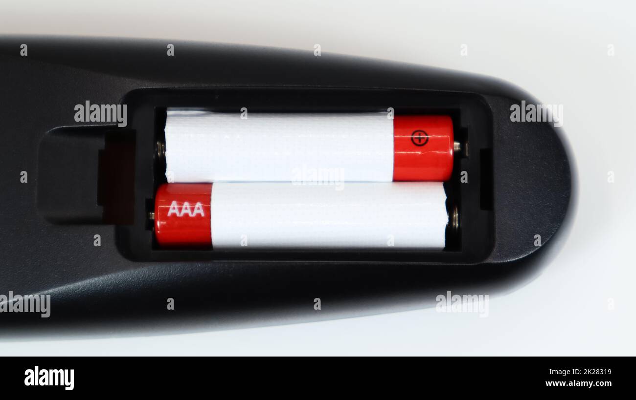 Télécommande noire avec piles alcalines AAA en rouge et blanc sur fond blanc. Remplacement de la batterie, pièces de rechange. Vue rapprochée du compartiment à piles de la télécommande. Banque D'Images