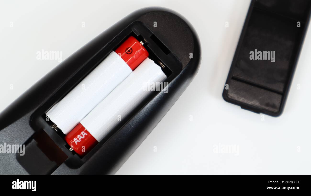 Télécommande noire avec piles alcalines AAA en rouge et blanc sur fond blanc. Remplacement de la batterie, pièces de rechange. Vue rapprochée du compartiment à piles de la télécommande. Banque D'Images
