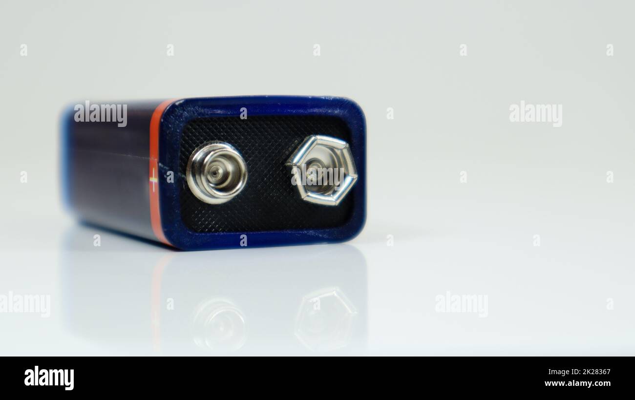 Un bleu utilisait une pile PP3 sur un fond blanc avec réflexion. Batterie principale pour alimentations personnelles. Vue rapprochée d'un connecteur de batterie usé et rayé. Banque D'Images