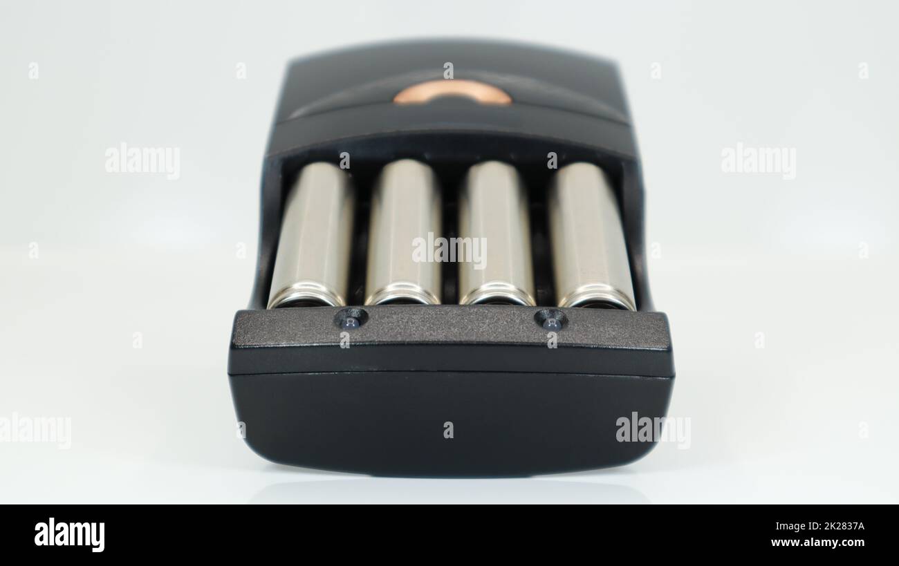 Piles alcalines rechargeables dans un chargeur sur fond blanc. Chargeur rapide AA en noir. La batterie est en cours de charge. Banque D'Images