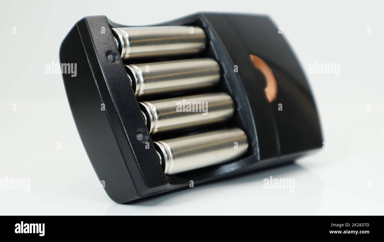 Piles alcalines rechargeables dans un chargeur sur fond blanc. Chargeur rapide AA en noir. La batterie est en cours de charge. Banque D'Images