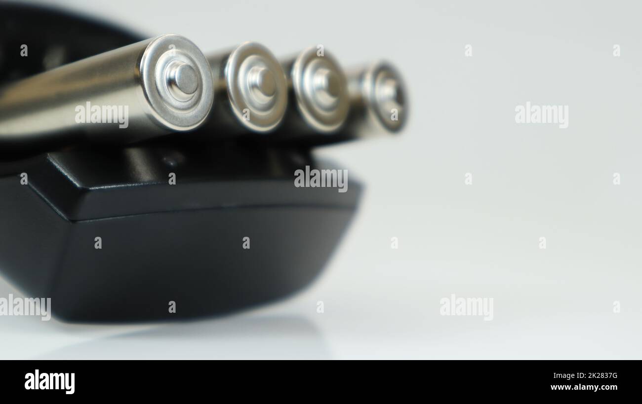 Piles alcalines rechargeables dans un chargeur sur fond blanc. Chargeur rapide AA en noir. La batterie est en cours de charge. Banque D'Images