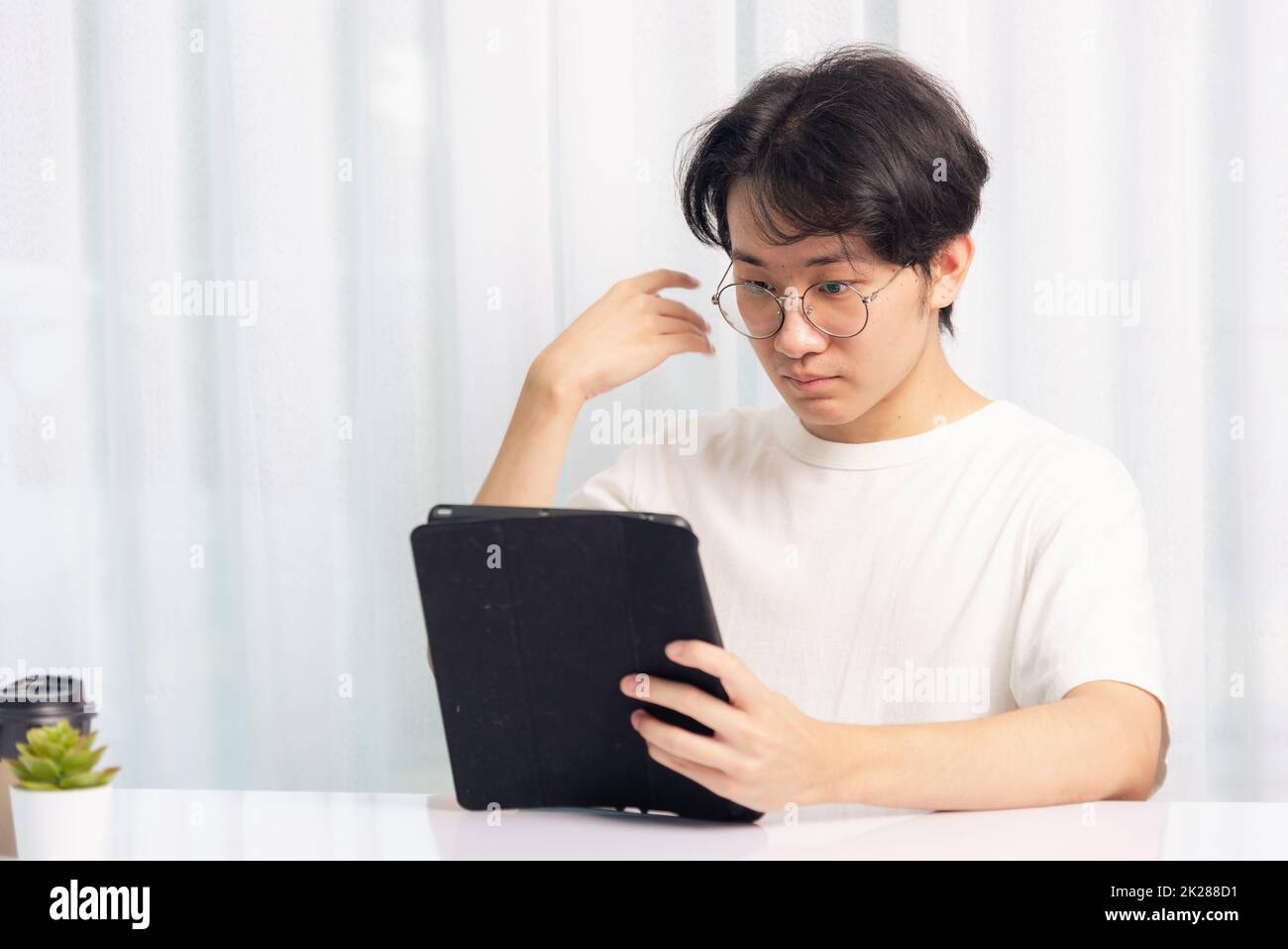 Un homme d'affaires travaille depuis son bureau à domicile, il utilise un noir tablette numérique intelligente et moderne Banque D'Images