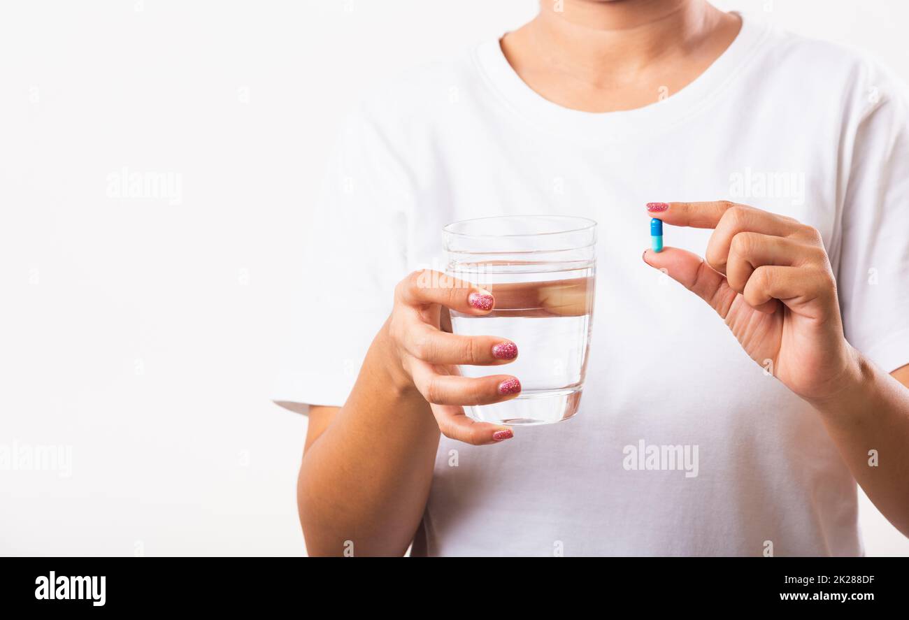 Femme tenir les médicaments de pilule dans la main prêt prendre des médicaments avec un verre d'eau Banque D'Images