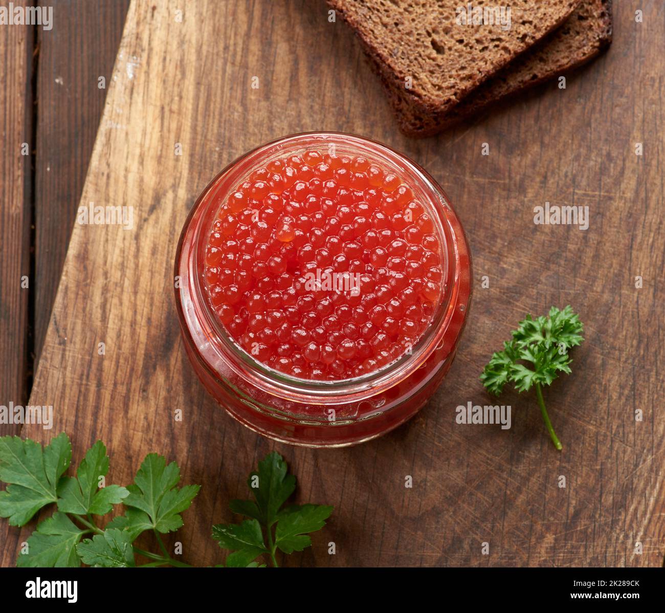 grand pot en verre avec caviar rouge sur une table en bois marron, vue de dessus Banque D'Images