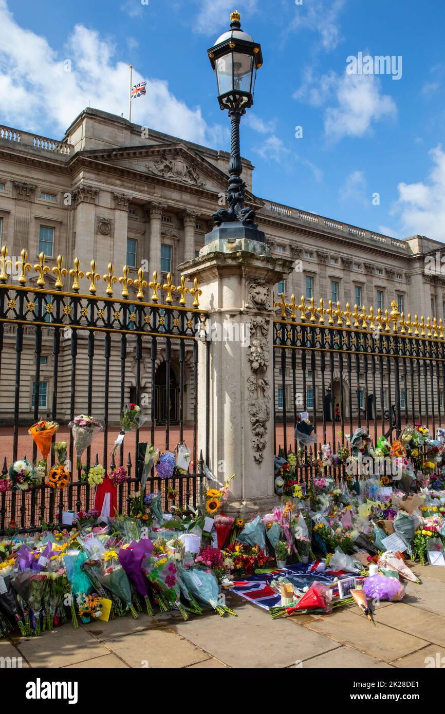 Londres, Royaume-Uni - 9 septembre 2022 : fleurs laissées par des adeptes et drapeau en Berne au palais de Buckingham à Londres, en commémoration d'Elizabeth Banque D'Images