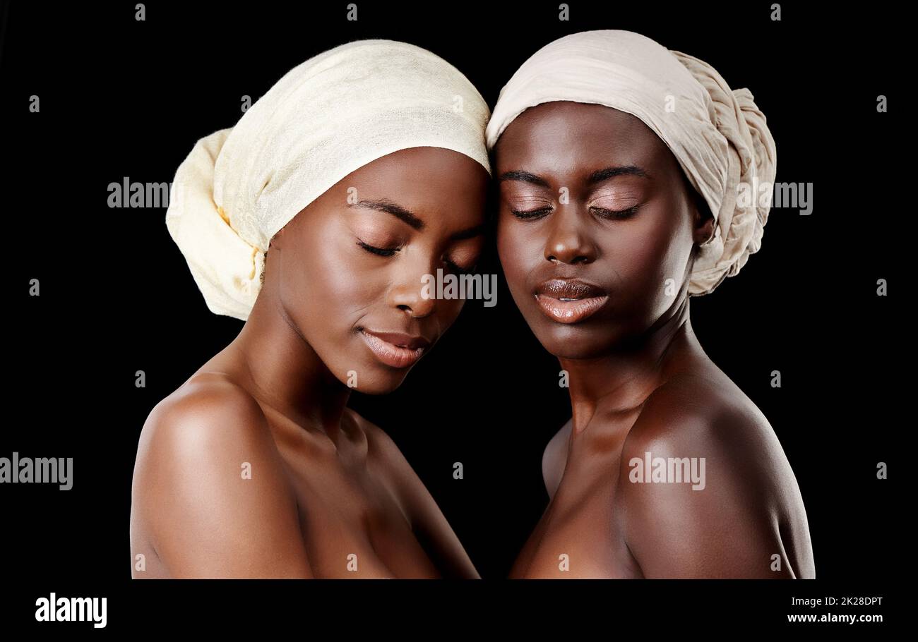 Deux petits pois dans une gousse. Photo en studio de deux belles femmes portant un foulard sur fond noir. Banque D'Images