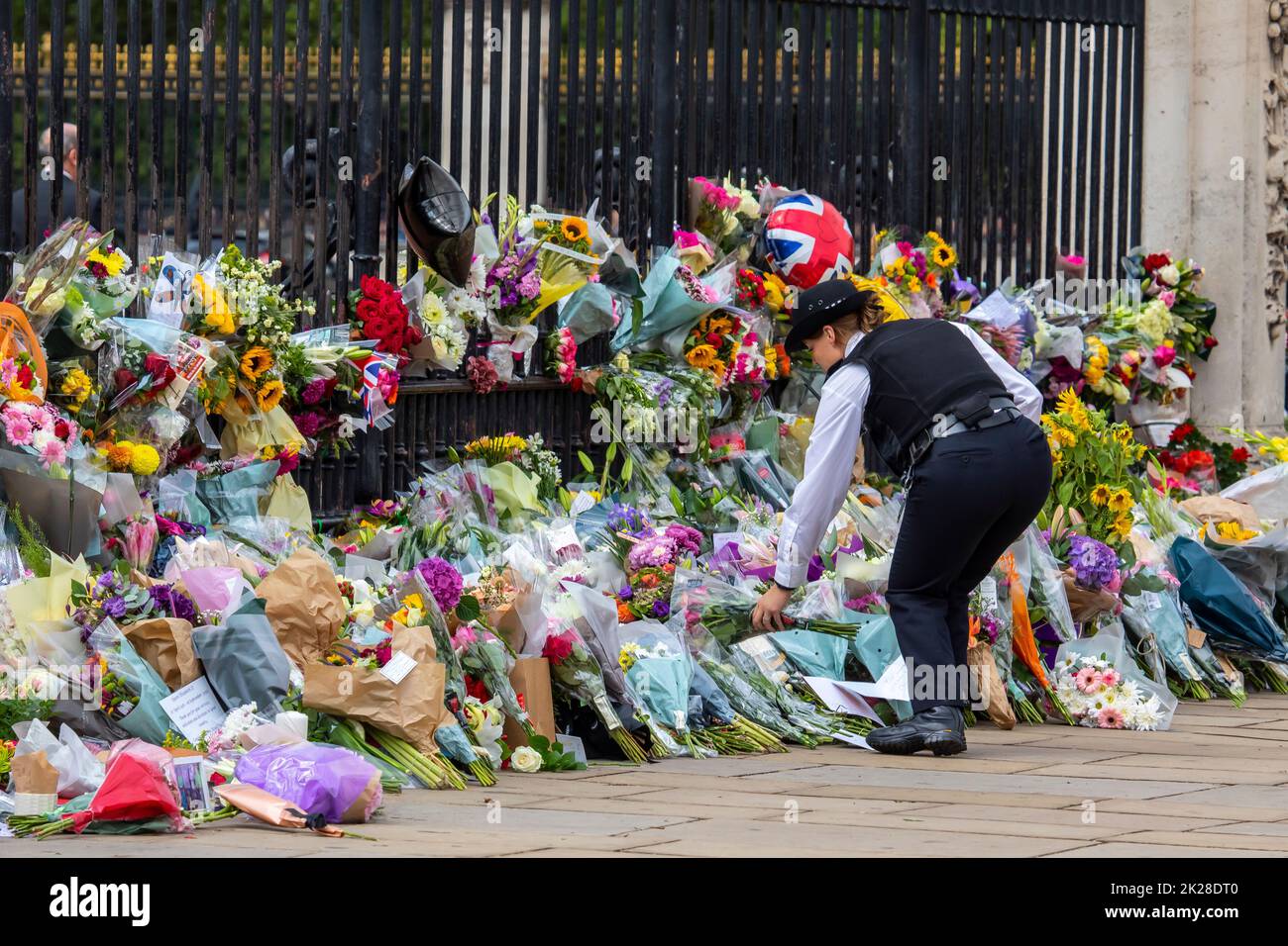 Londres, Royaume-Uni - 9 septembre 2022 : un policier qui place des fleurs devant les portes de Buckingham Palace à Londres, en mémoire de la reine Elizabeth II, Banque D'Images
