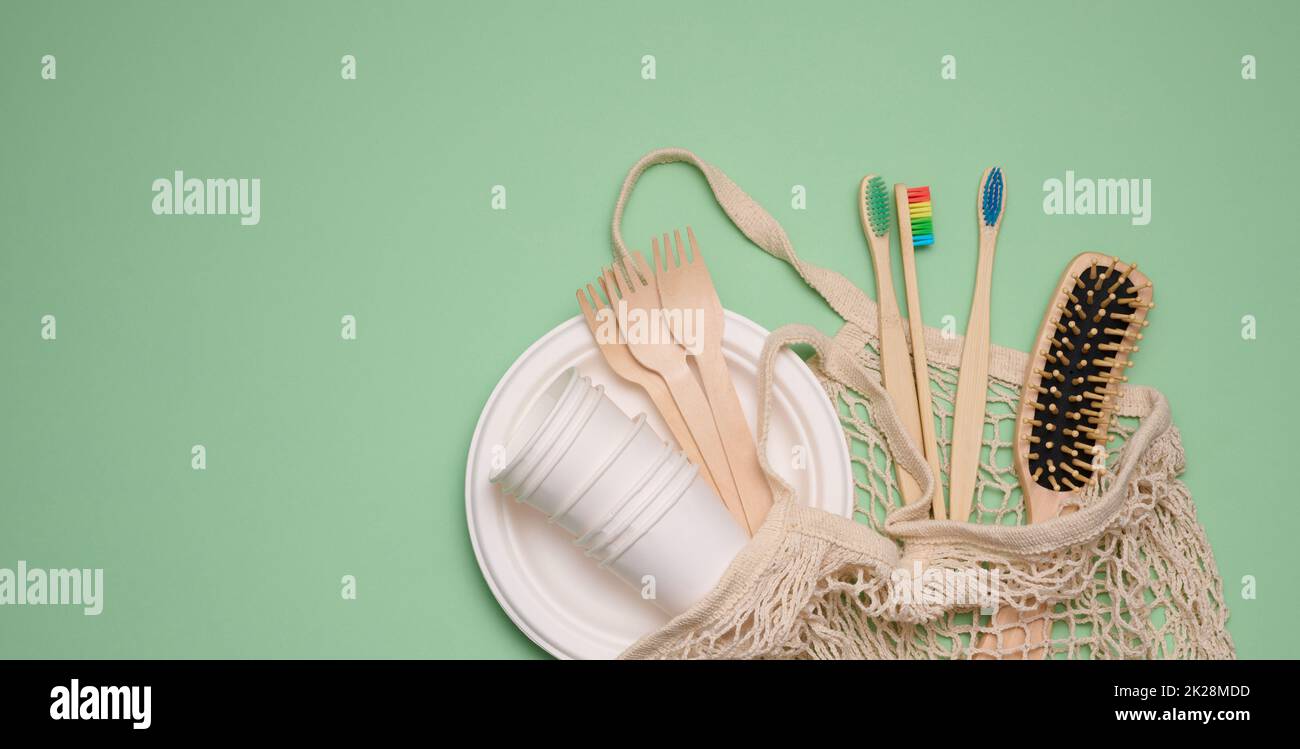 sac en coton blanc, gobelets en papier et brosses à dents en bois sur fond vert, espace de copie Banque D'Images