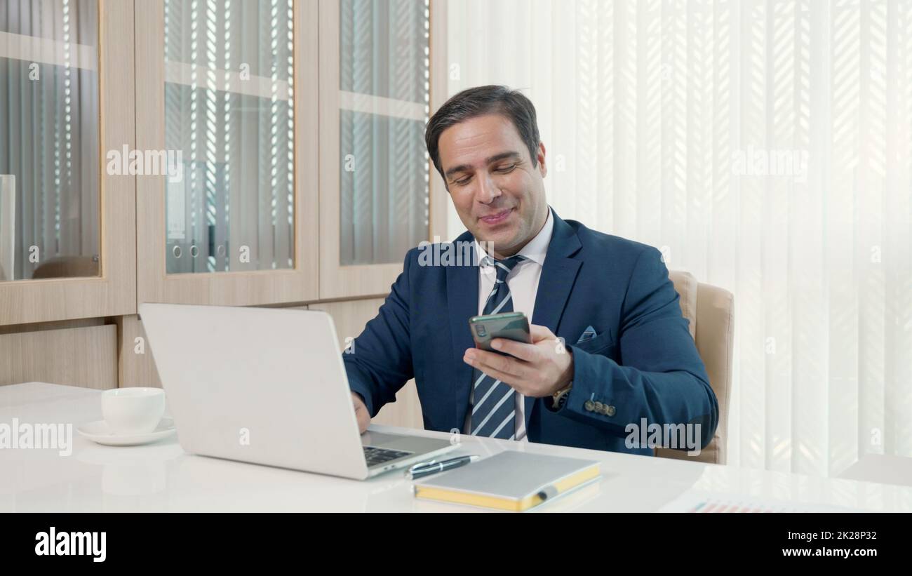 Homme d'affaires assis à l'aide d'un ordinateur portable étudier travail en ligne à son bureau célébration de succès au bureau Banque D'Images