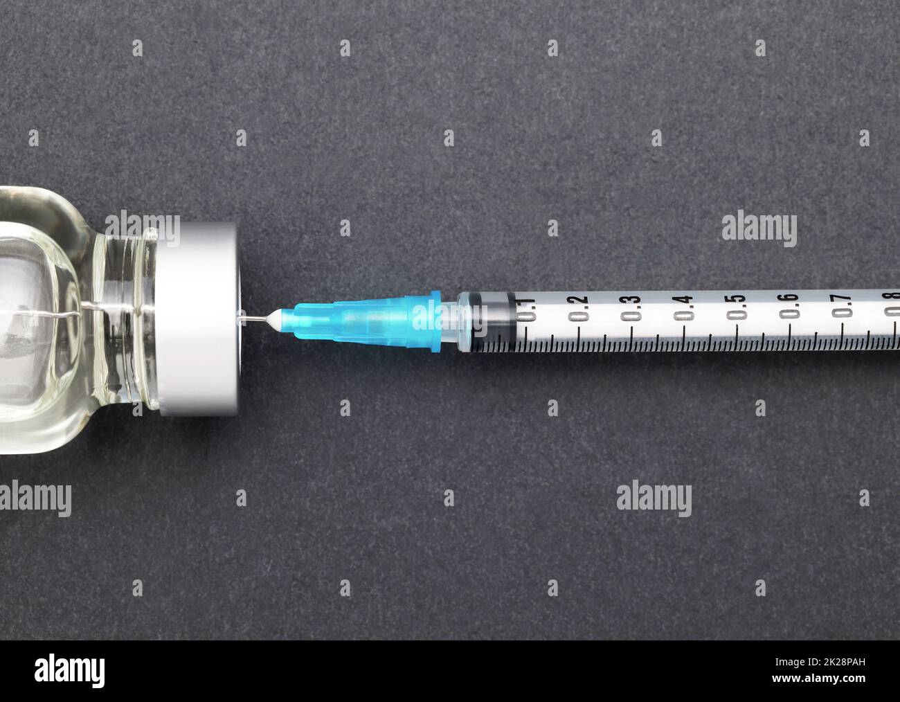 Médicament liquide en flacons et seringue d'injection sur fond gris foncé Banque D'Images