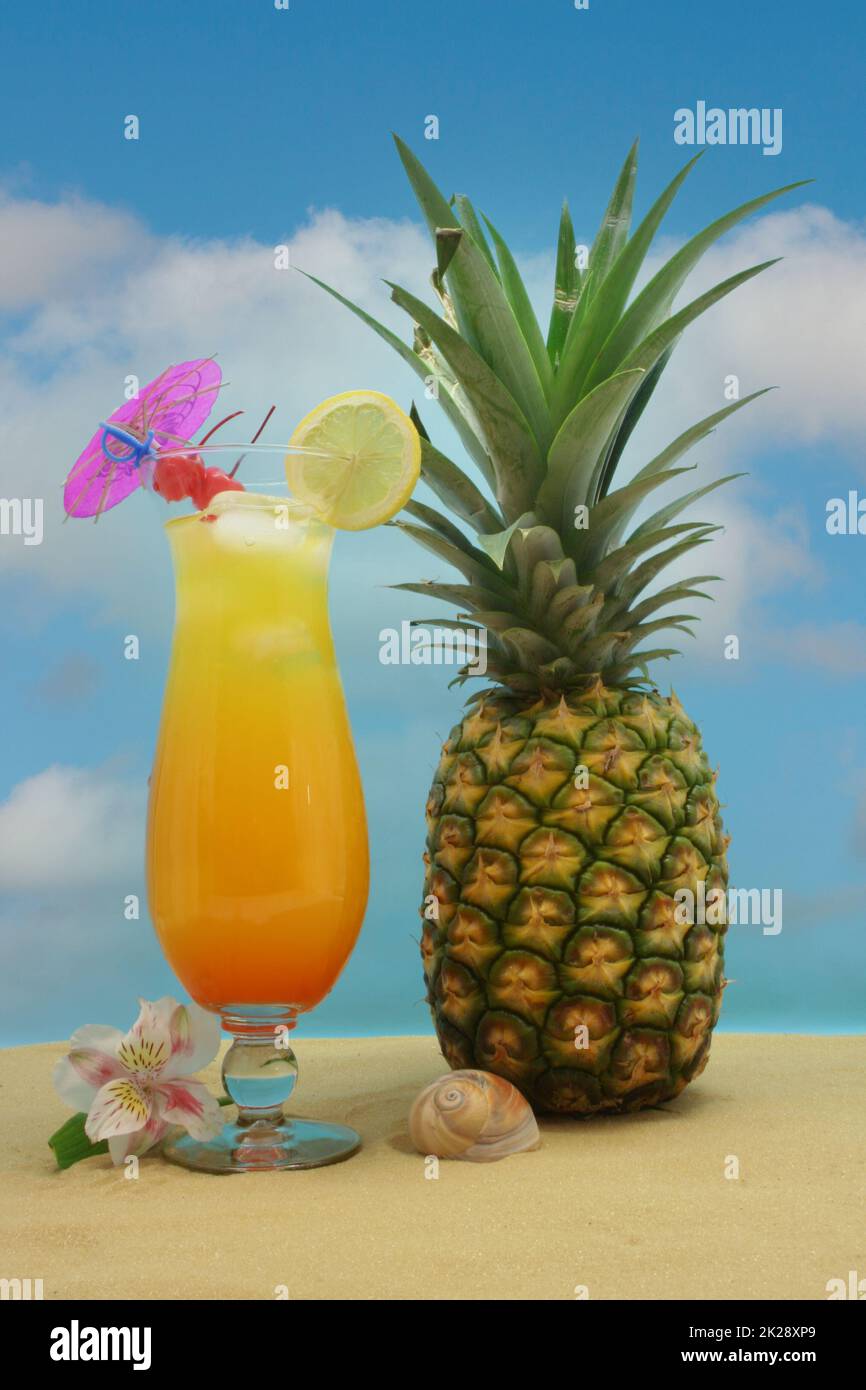 Ananas, boisson tropicale et fruits sur sable avec ciel Banque D'Images