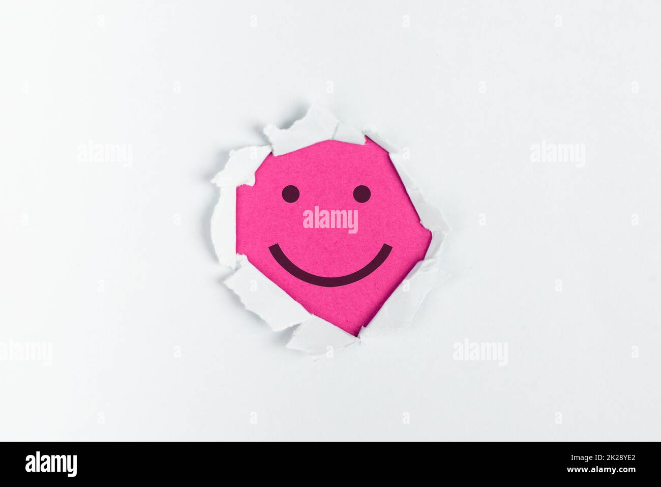 Sourire visage heureux sous un papier déchiré, émotions positives, bons commentaires des clients, rire Banque D'Images