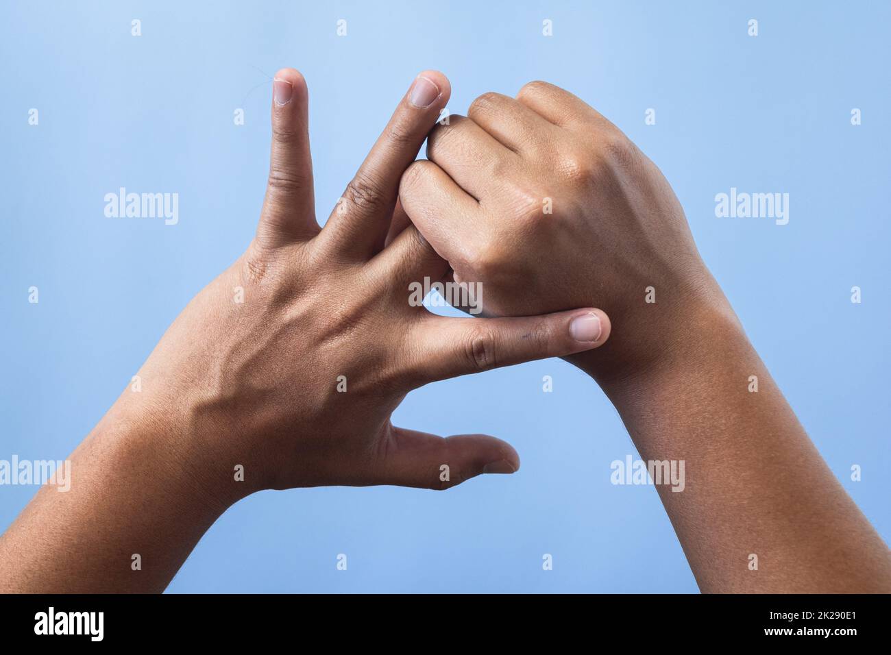 Concept de syndrome de bureau. Le doigt du milieu est massant et étiré après le travail. Gros plan isoler sur fond bleu. Vue arrière. Banque D'Images