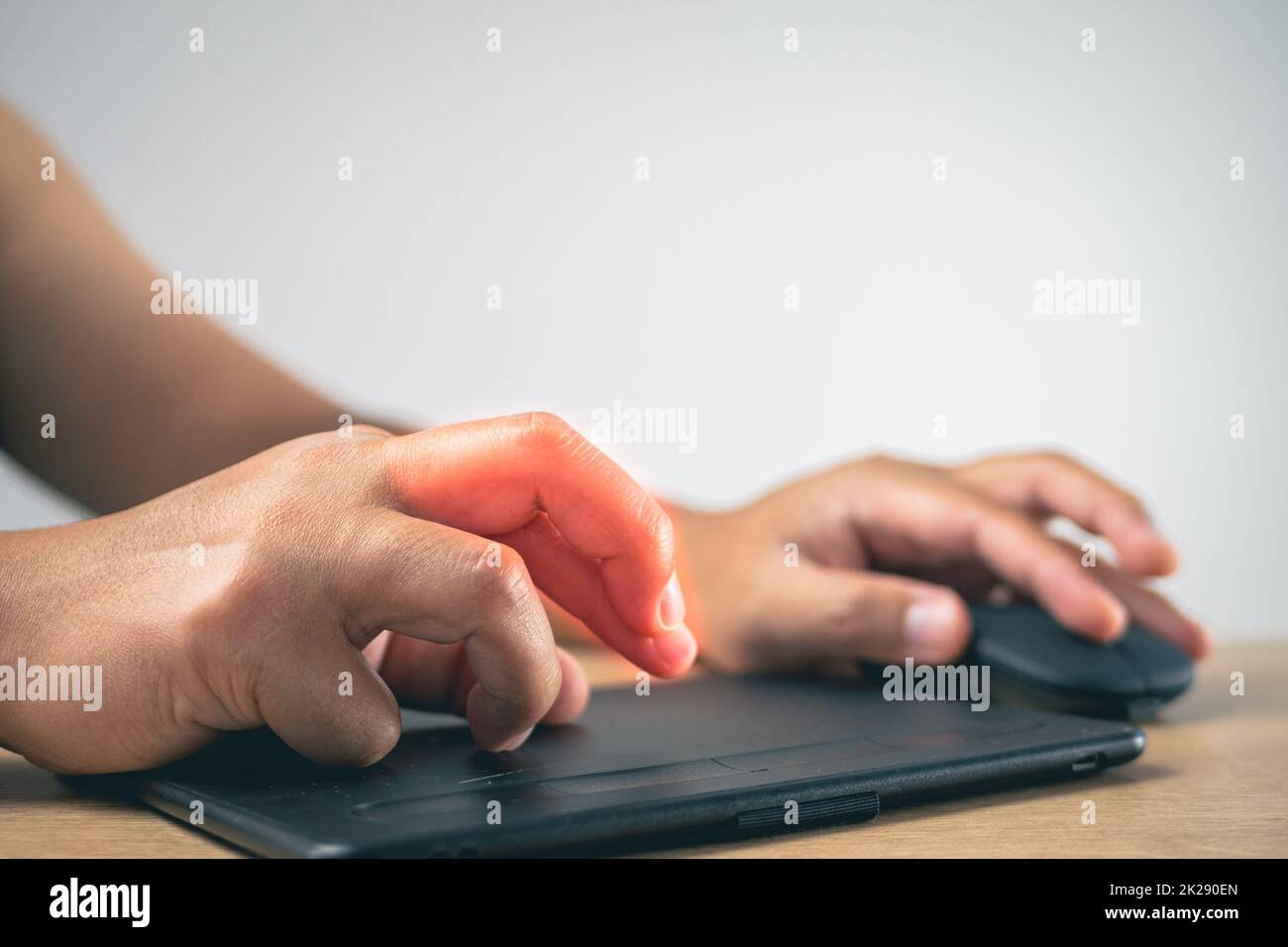 L'homme utilise une souris et un tapis de dessin jusqu'à ce que ses doigts douleurs. Concept de syndrome de bureau. La zone des symptômes de douleur est indiquée en rouge. Gros plan moyen avec espace de copie. Banque D'Images