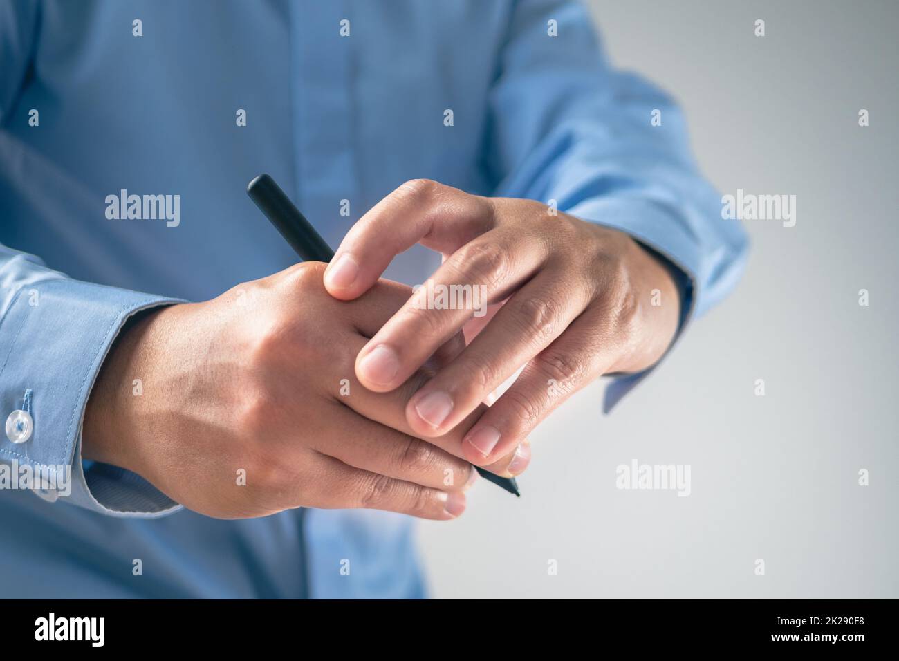 L'homme utilise un stylo jusqu'à ce que ses doigts douleur. Concept de syndrome de bureau. Gros plan moyen avec un peu d'espace de copie. Banque D'Images