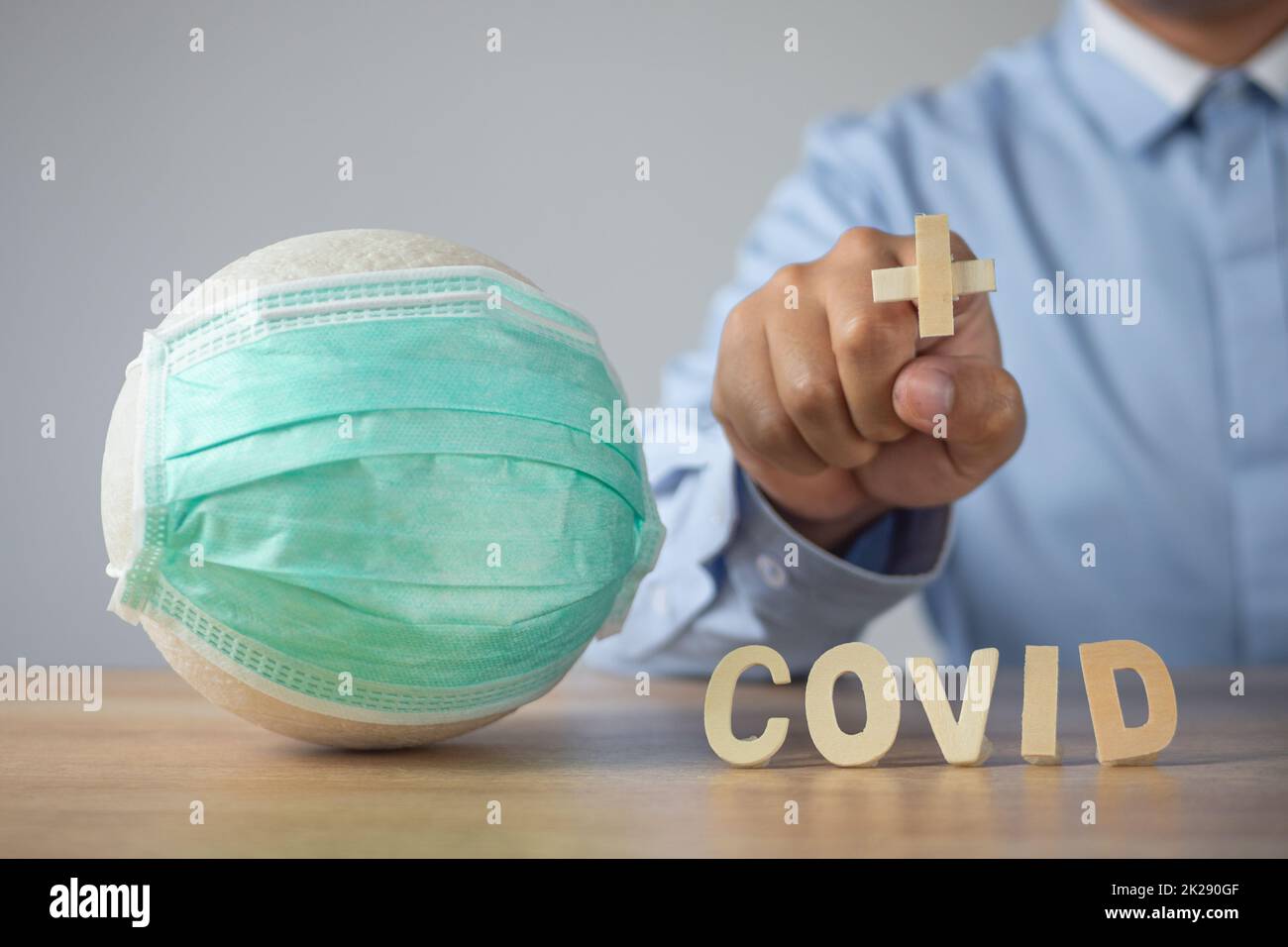 Assurance maladie en coronavirus concept. Forme plus sur le doigt d'homme. Boule blanche avec masque médical vert sur la table. Banque D'Images