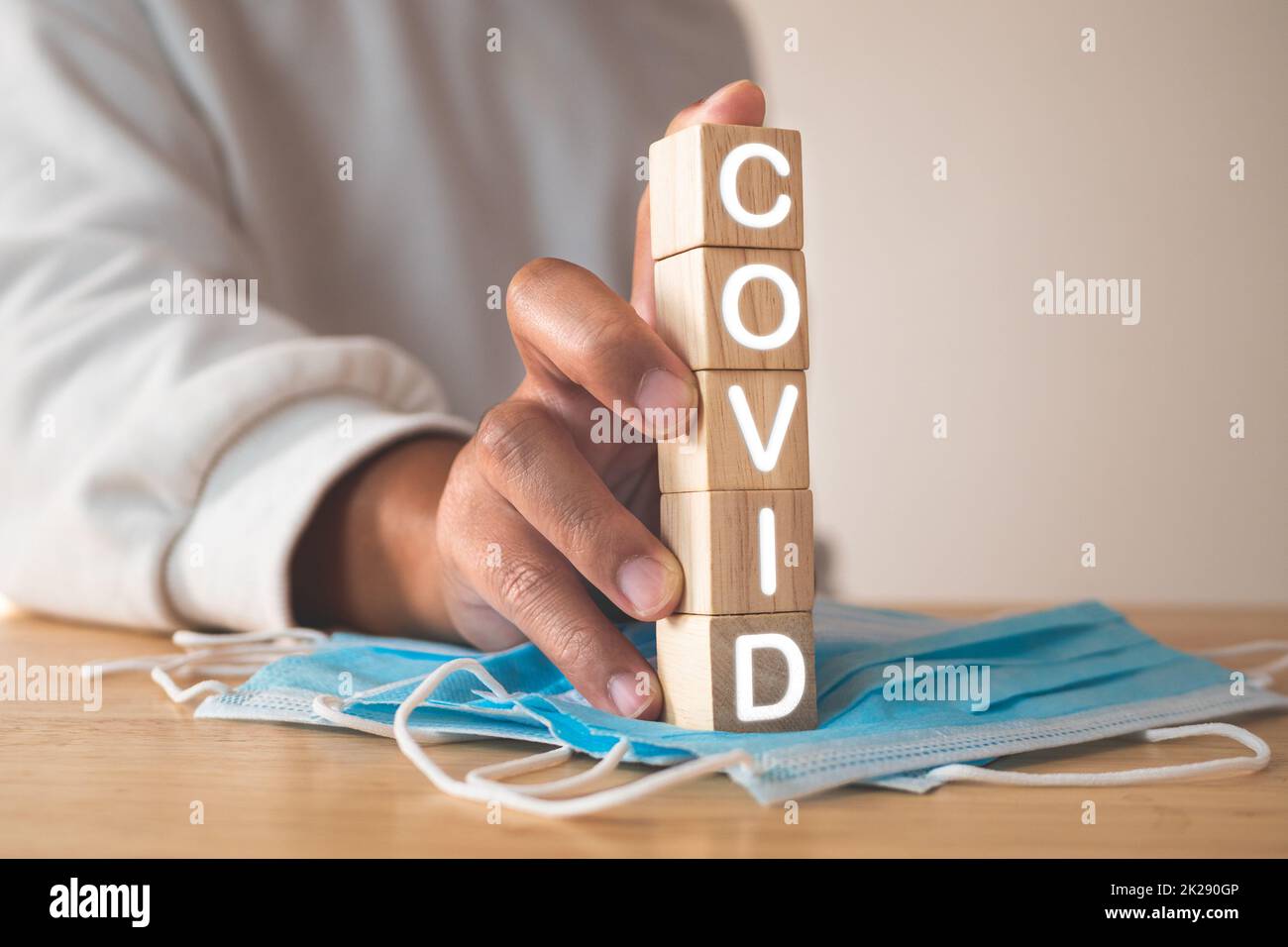 Ce concept montre une campagne pour un port correct du masque. Blocs de bois avec texte, COVID. Masque médical bleu sur la table. Protection contre les maladies telles que la grippe, la grippe, Covid, Dust, PM2,5. Banque D'Images