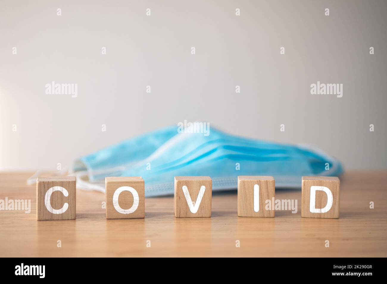 Ce concept montre une campagne pour un port correct du masque. Blocs de bois avec texte, COVID. Masque médical bleu sur la table. Protection contre les maladies telles que la grippe, la grippe, Covid, Dust, PM2,5. Banque D'Images