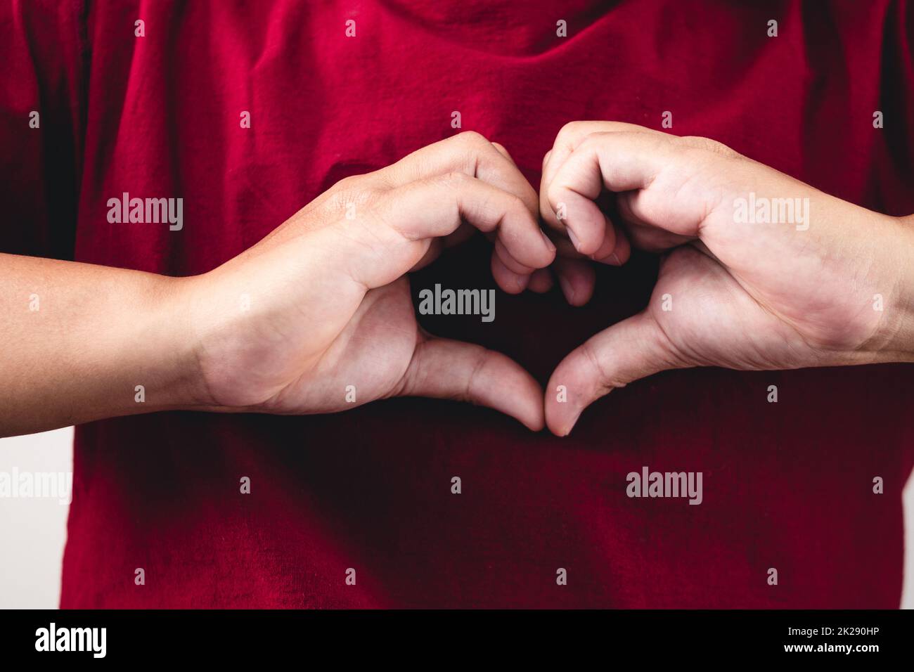 La personne montre des mains signe d'amour près de la poitrine. L'homme avec une chemise rouge en gros plan moyen. Banque D'Images