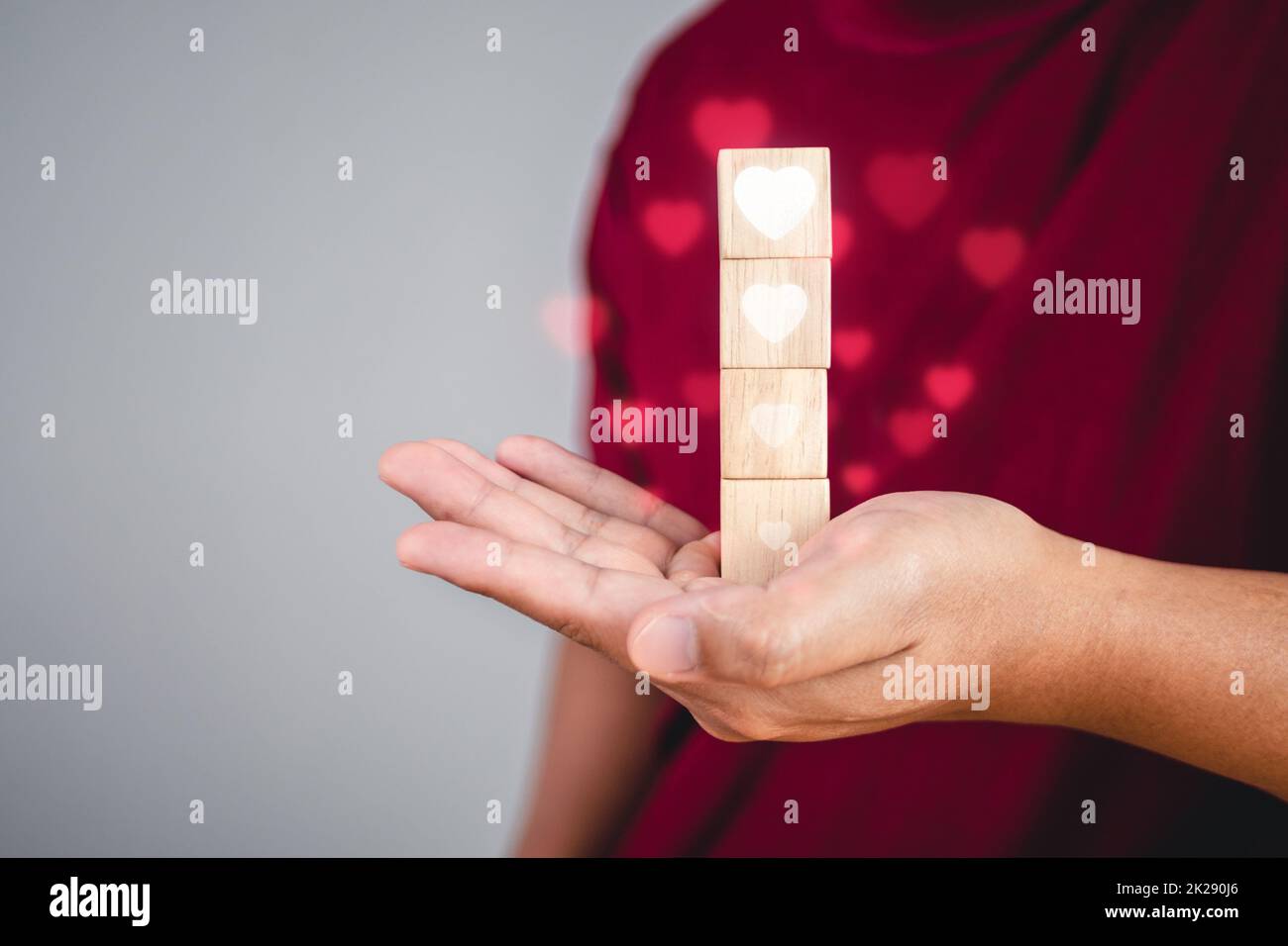 Concept de la Saint-Valentin. Quelqu'un tient des blocs de bois qui montre des niveaux d'amour de haut en bas, plus à moins, respectivement. La forme de coeur blanc est conçue sous forme d'effet visuel. Banque D'Images