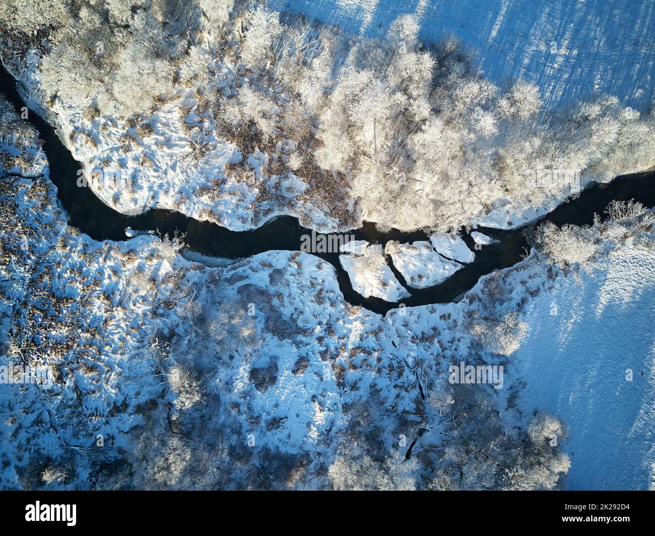 Forêt d'hiver avec vue aérienne sur le toit gelé. Arbres sur la rive. Petit ruisseau en forêt. Route de terre rurale. Paysage recouvert de neige. Temps froid Banque D'Images