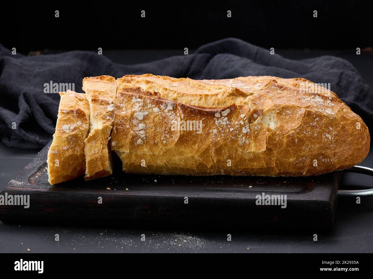 pain ovale entier cuit à la farine de blé blanc sur une table noire, pâtisseries fraîches Banque D'Images