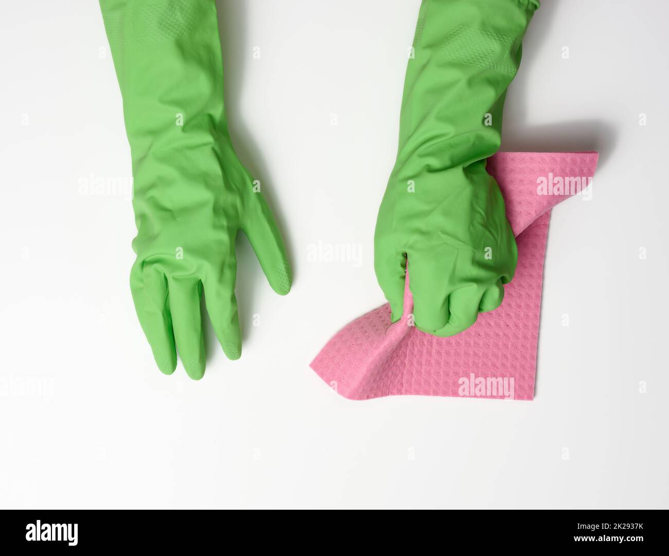 main dans un gant en caoutchouc vert contient une éponge douce pour nettoyer les surfaces sur un fond blanc Banque D'Images