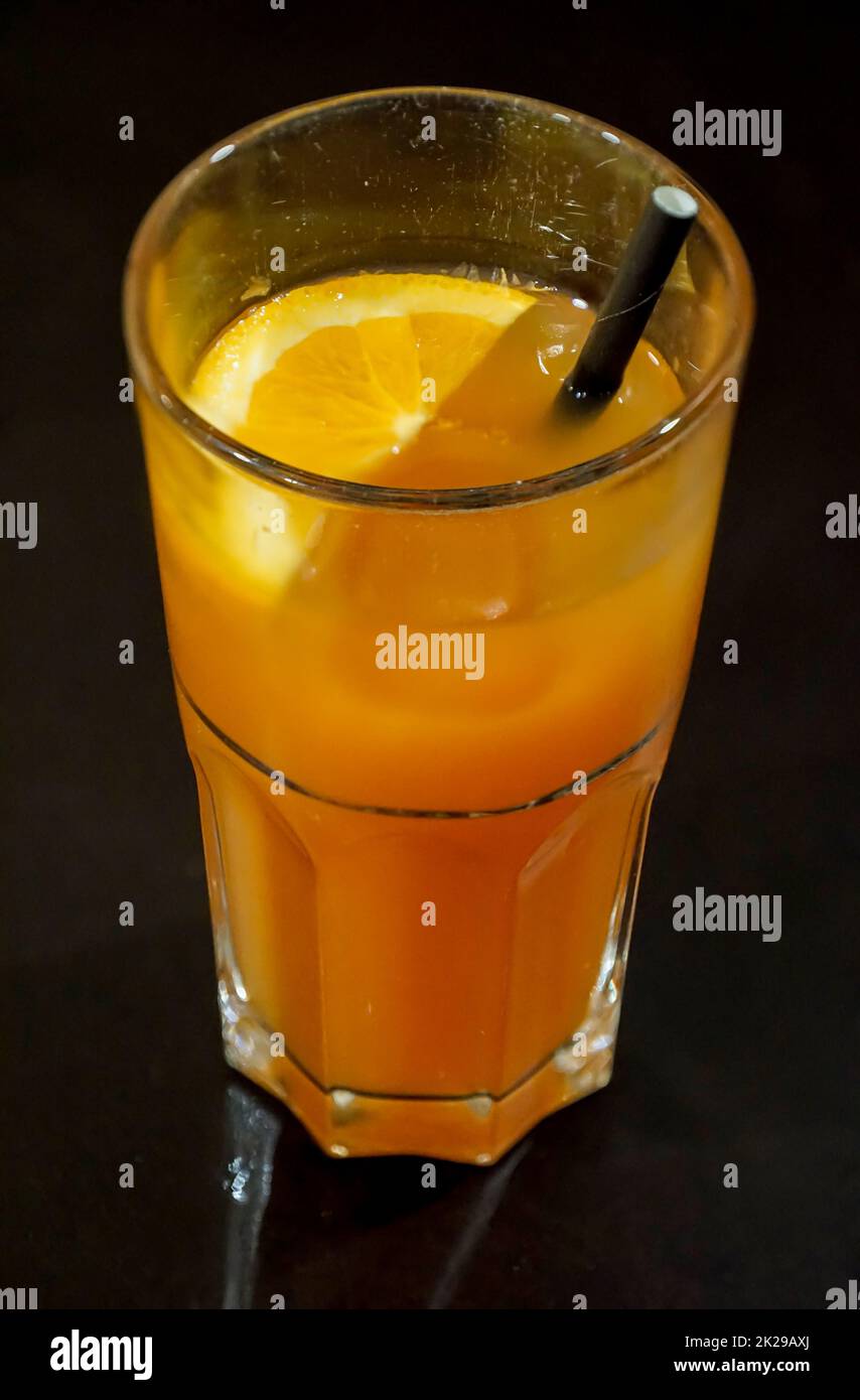 Un verre pour une boisson, un jus d'orange avec de la paille. Banque D'Images