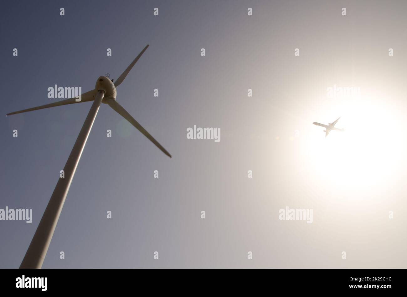 Avion et éolienne contre la lumière. Banque D'Images